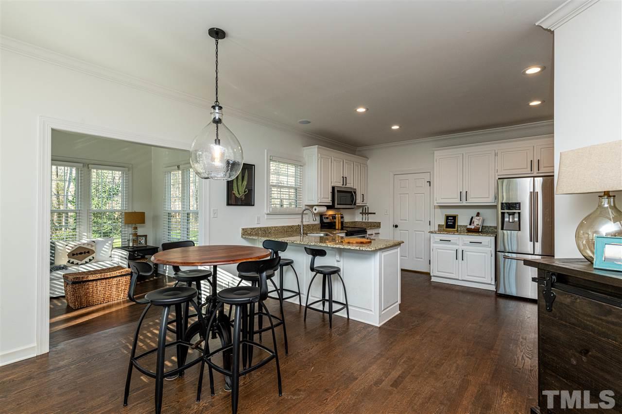 8105 Iron Bark Court Raleigh, NC 27606 - Photo 10 of 30 a kitchen with stainless steel appliances kitchen island granite countertop a table chairs sink and cabinets