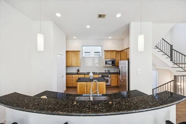 a kitchen with kitchen island granite countertop a sink a stove and a refrigerator