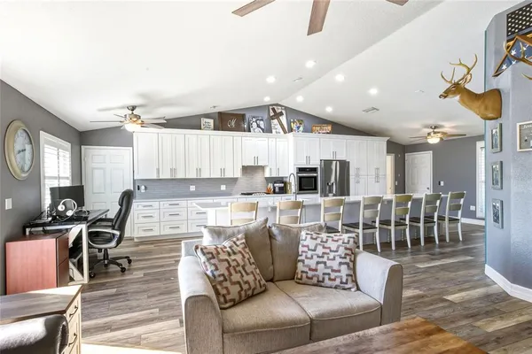 a living room with furniture kitchen view and a wooden floor