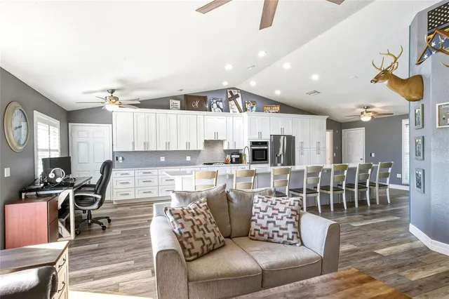 a living room with furniture kitchen view and a wooden floor