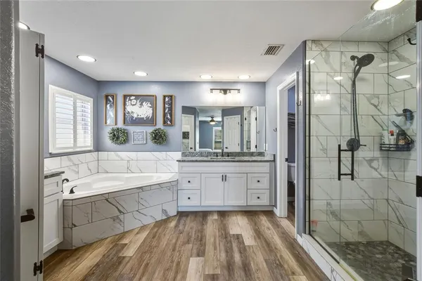 a spacious bathroom with a tub sink shower and mirror