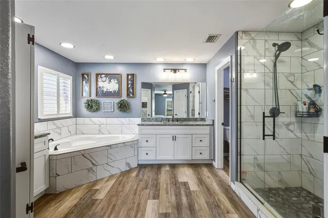 a spacious bathroom with a tub sink shower and mirror