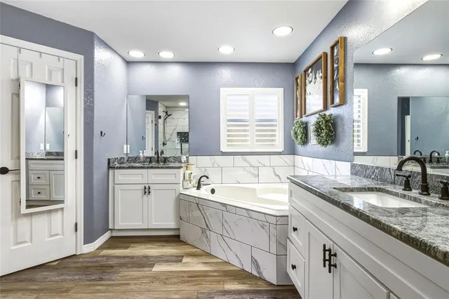 a spacious bathroom with a granite countertop sink mirror and bathtub