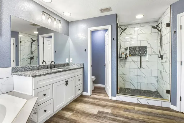 a bathroom with a granite countertop sink mirror and shower