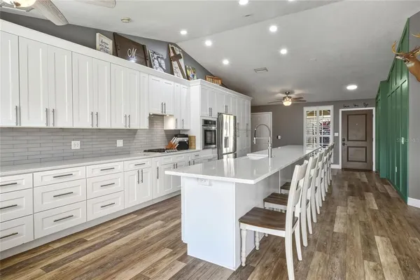 a large white kitchen with wooden floors and white cabinets
