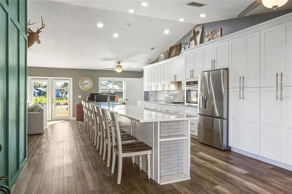 a kitchen with stainless steel appliances granite countertop a refrigerator oven a sink a dining table and chairs with wooden floor