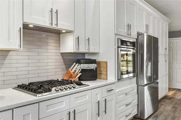 a kitchen with stainless steel appliances granite countertop a stove a refrigerator and a white cabinets