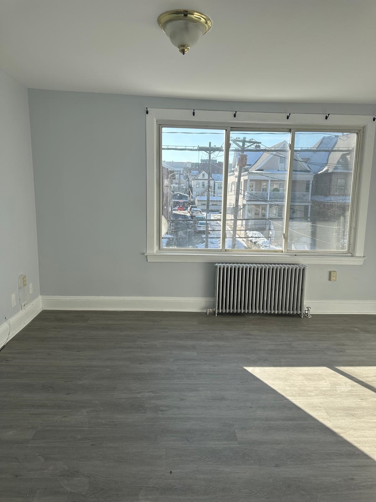 31 East 32nd Street, Unit 2 Bayonne, NJ 07002 - Photo 13 of 19 an empty room with wooden floor and windows