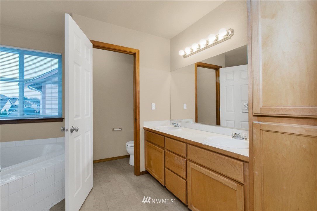 6912 Radius Loop Southeast Lacey, WA 98513 - Photo 19 of 30 a spacious bathroom with a double vanity sink a mirror and a bathtub