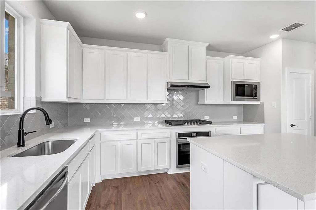 6246 Shasta Creek Road Celina, TX 75009 - Photo 8 of 24 a kitchen with granite countertop white cabinets and white appliances