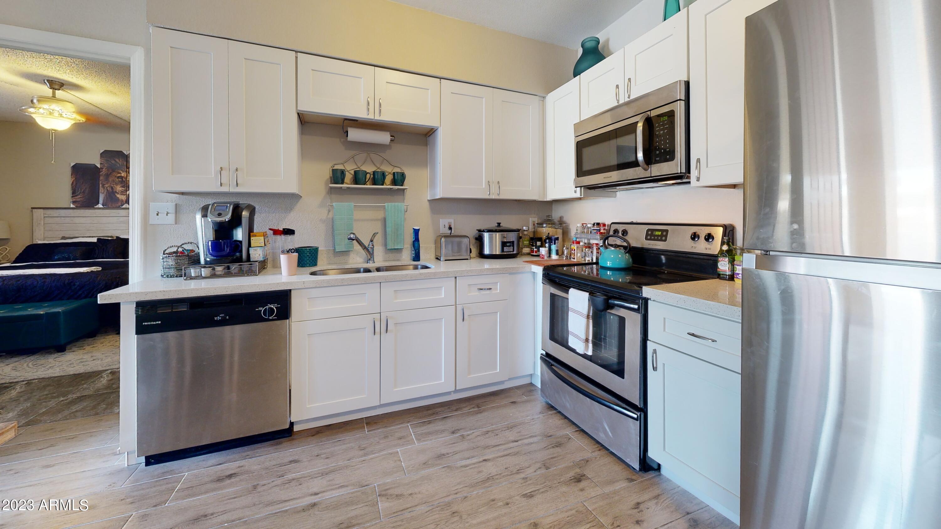 1440 North Idaho Road, Unit 1098 Apache Junction, AZ 85119 - Photo 1 of 10 a kitchen with stainless steel appliances granite countertop a stove a sink and a microwave