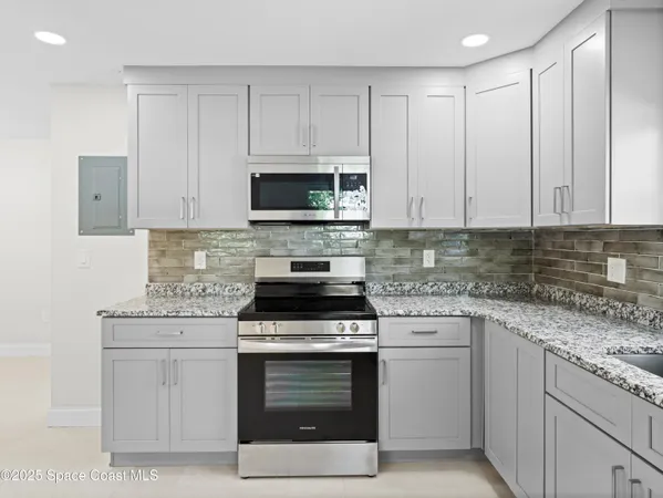 a kitchen with stainless steel appliances granite countertop a refrigerator sink and white cabinets