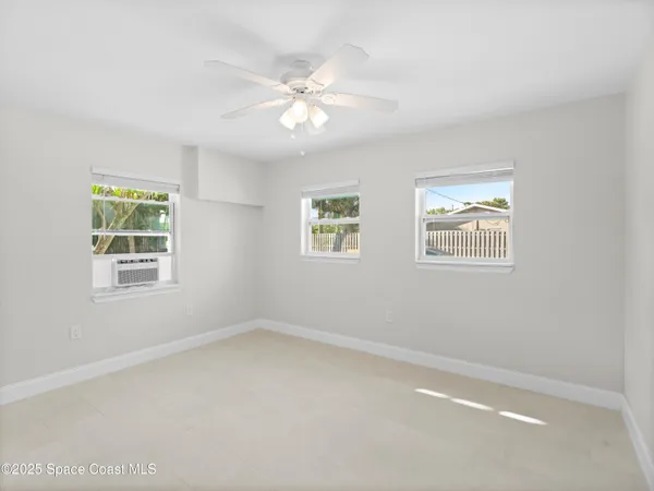 an empty room with windows and fan