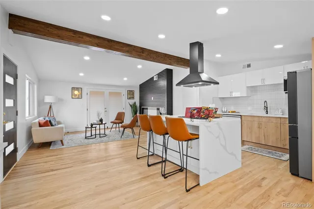 a living room with stainless steel appliances furniture and a wooden floor