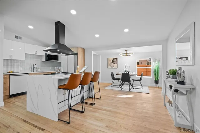 a living room with furniture and kitchen view with wooden floor