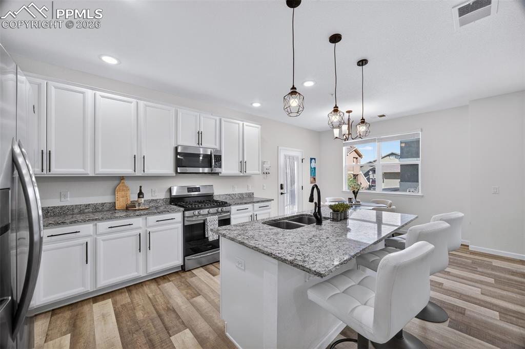 a kitchen with kitchen island granite countertop stainless steel appliances a sink stove and white cabinets
