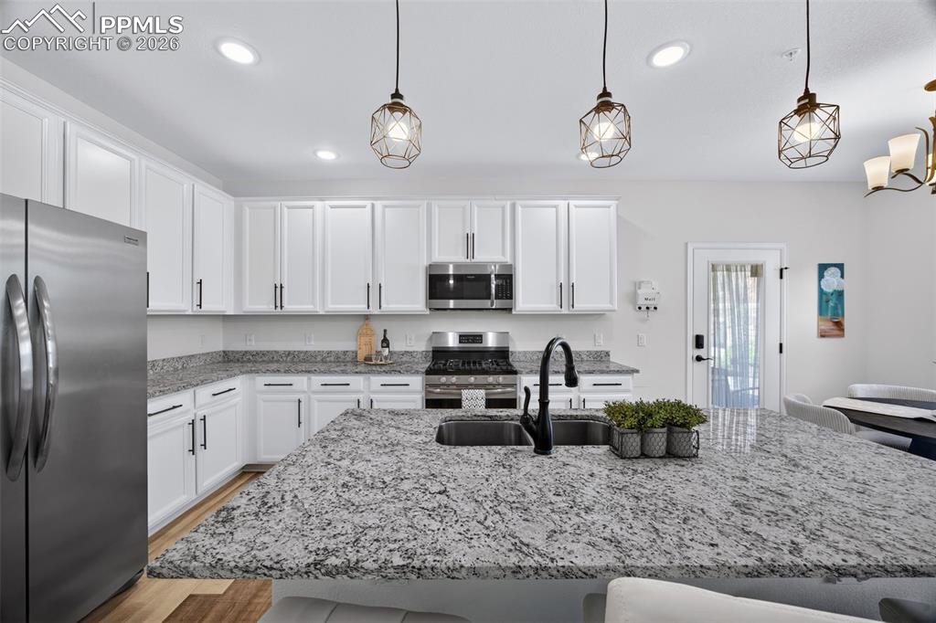 4658 Copeland Circle, Unit 103 Highlands Ranch, CO 80126 - Photo 11 of 37 a kitchen with stainless steel appliances granite countertop a sink a stove a refrigerator cabinets and living room view