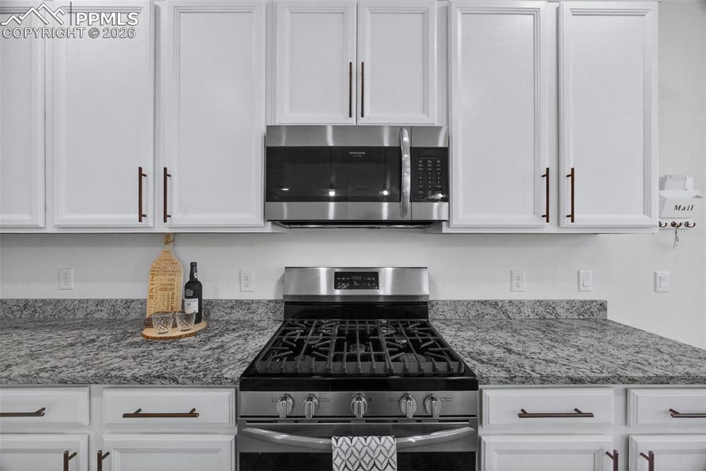 4658 Copeland Circle, Unit 103 Highlands Ranch, CO 80126 - Photo 10 of 37 a kitchen with stainless steel appliances granite countertop white cabinets and a stove
