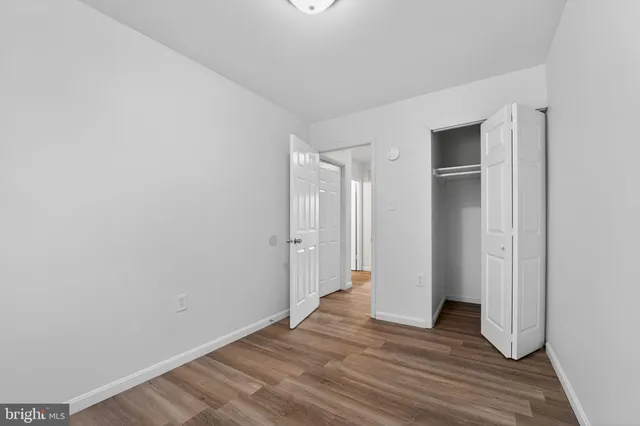 a view of an empty room with wooden floor and closet