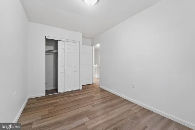 a view of an empty room with wooden floor and closet