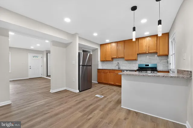 a kitchen with stainless steel appliances granite countertop a refrigerator a sink a stove a microwave and wooden floor