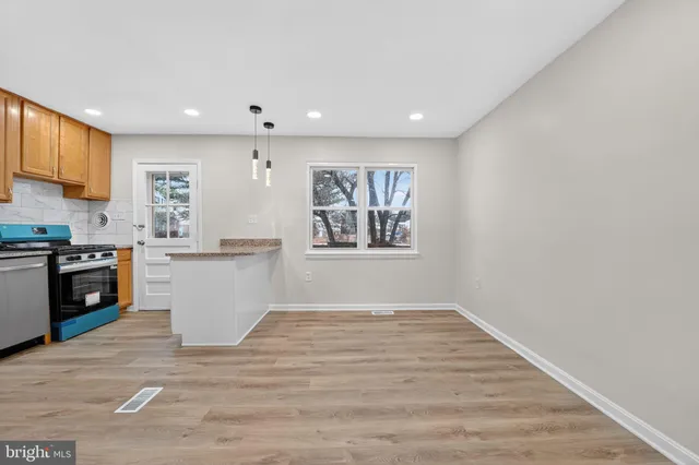 a view of a kitchen with wooden floor and stainless steel appliances