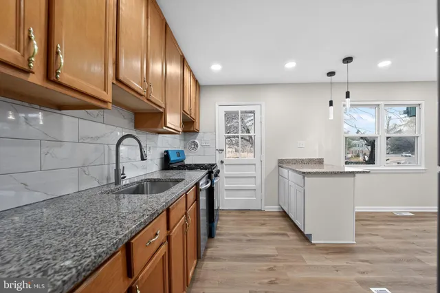 a kitchen with stainless steel appliances granite countertop a sink counter space cabinets and wooden floor