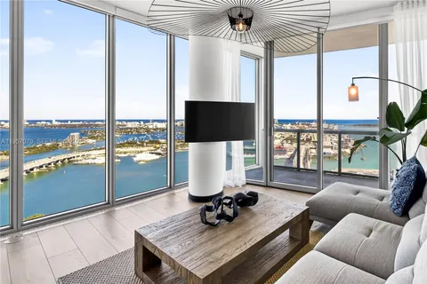 a living room with furniture a flat screen tv and a floor to ceiling window
