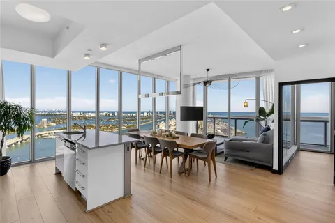 a open dining room with stainless steel appliances kitchen island granite countertop a table chairs and a living room
