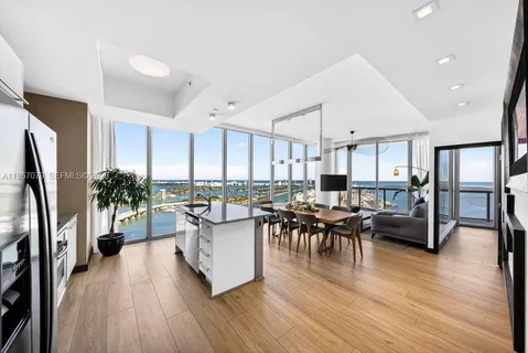 a living room with furniture a wooden floor and a view of kitchen