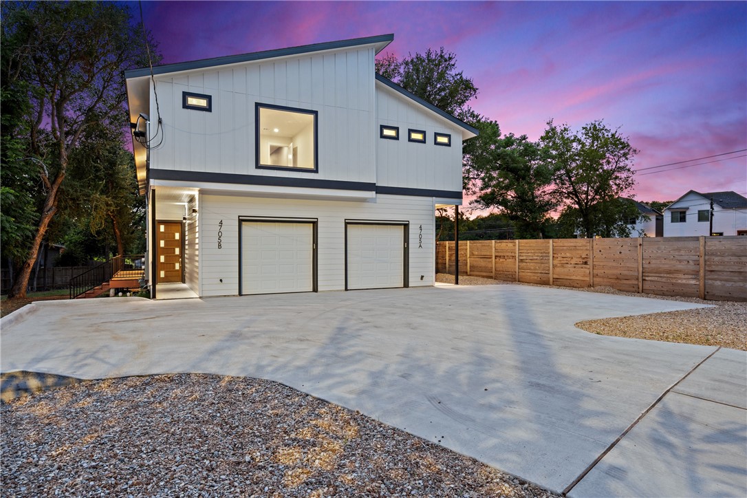 Property exterior at dusk featuring concrete driveway, fence, board and batten siding, and a garage