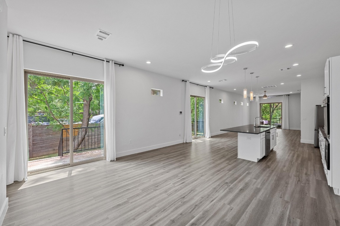 4705 Louis Avenue, Unit B Austin, TX 78721 - Photo 38 of 39 Kitchen with dark countertops, a sink, open floor plan, white cabinetry, and recessed lighting