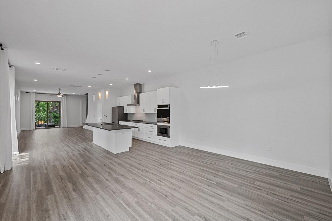 4705 Louis Avenue, Unit B Austin, TX 78721 - Photo 37 of 39 Kitchen with dark countertops, a sink, open floor plan, stainless steel appliances, and wall chimney exhaust hood