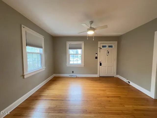 an empty room with wooden floor and windows