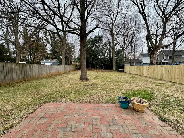 a view of a backyard with large tree and wooden fence