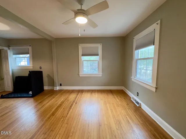 a view of an empty room with a window and wooden floor