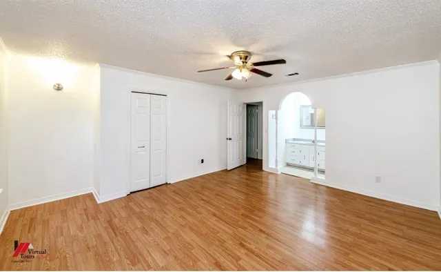 a view of empty room with wooden floor and fan