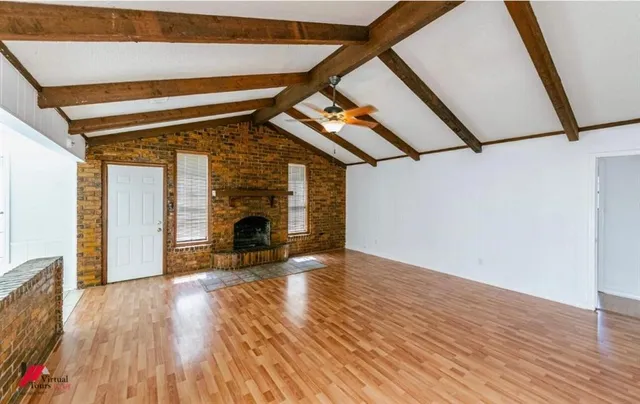 a view of a livingroom with wooden floor and a fireplace