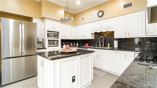 a kitchen with stainless steel appliances granite countertop a refrigerator a sink and white cabinets
