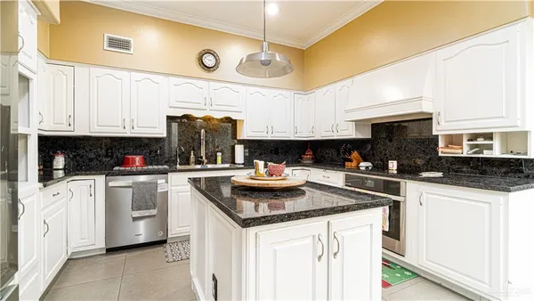 a kitchen with granite countertop a sink stainless steel appliances and white cabinets
