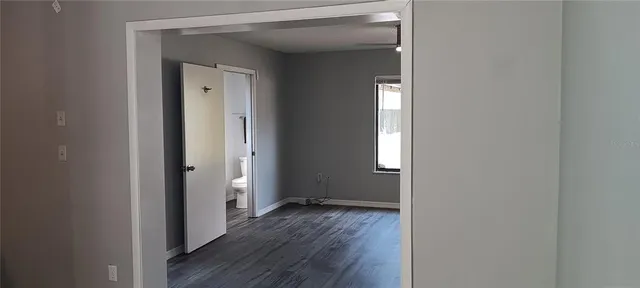 a view of an empty room with wooden floor and a window