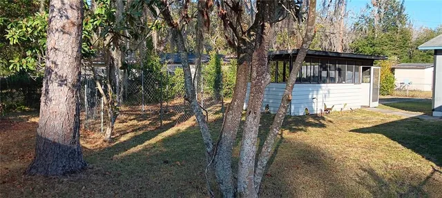 a view of a house with backyard and trees