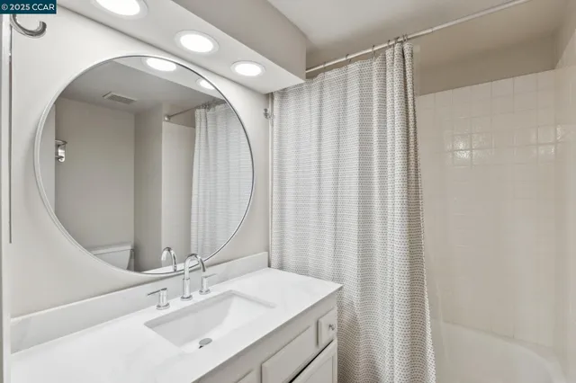 a bathroom with a sink vanity mirror and a shower
