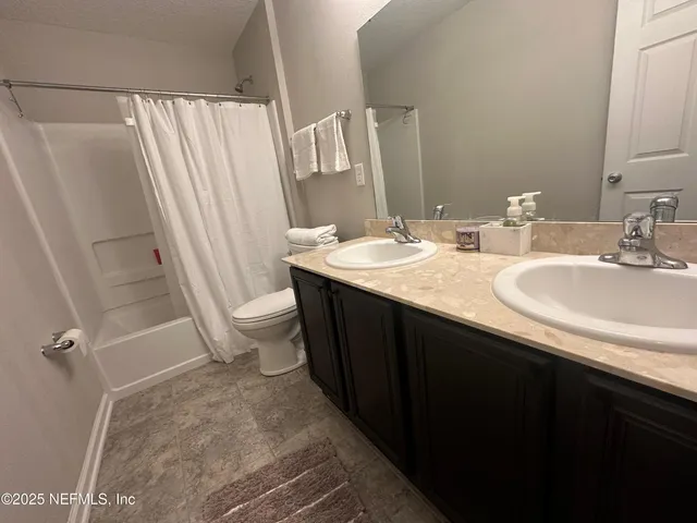 a bathroom with a sink a toilet a mirror and shower