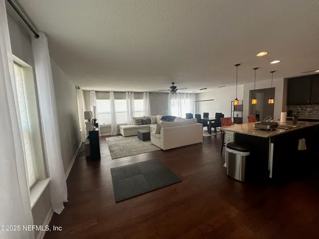 a living room with couches and kitchen view with wooden floor