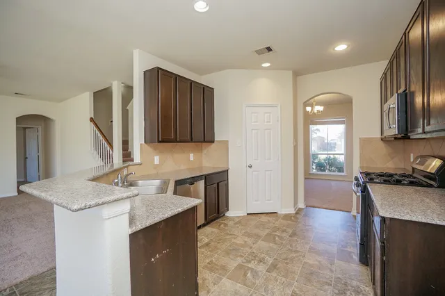 a kitchen with granite countertop a sink a stove and a wooden cabinets