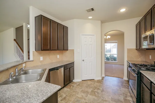 a kitchen with stainless steel appliances granite countertop a stove a sink and a microwave