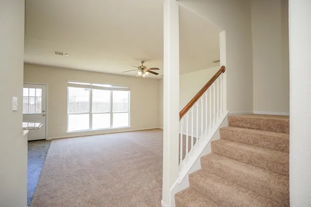 an empty room with chandelier fan and windows