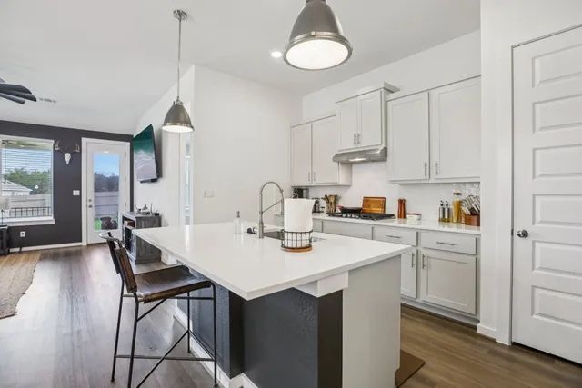 a kitchen with stainless steel appliances granite countertop a sink a stove and chairs