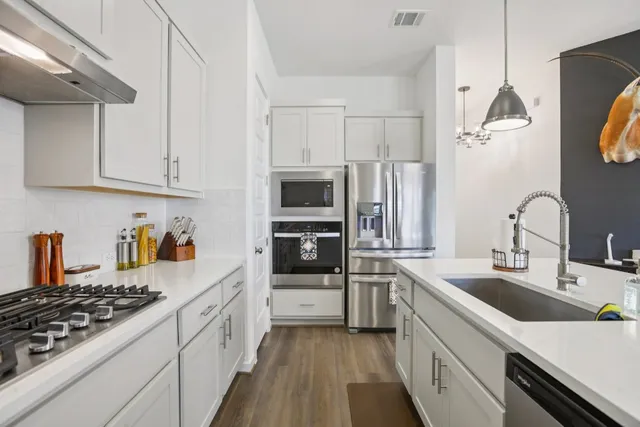a kitchen with stainless steel appliances a stove sink microwave and cabinets